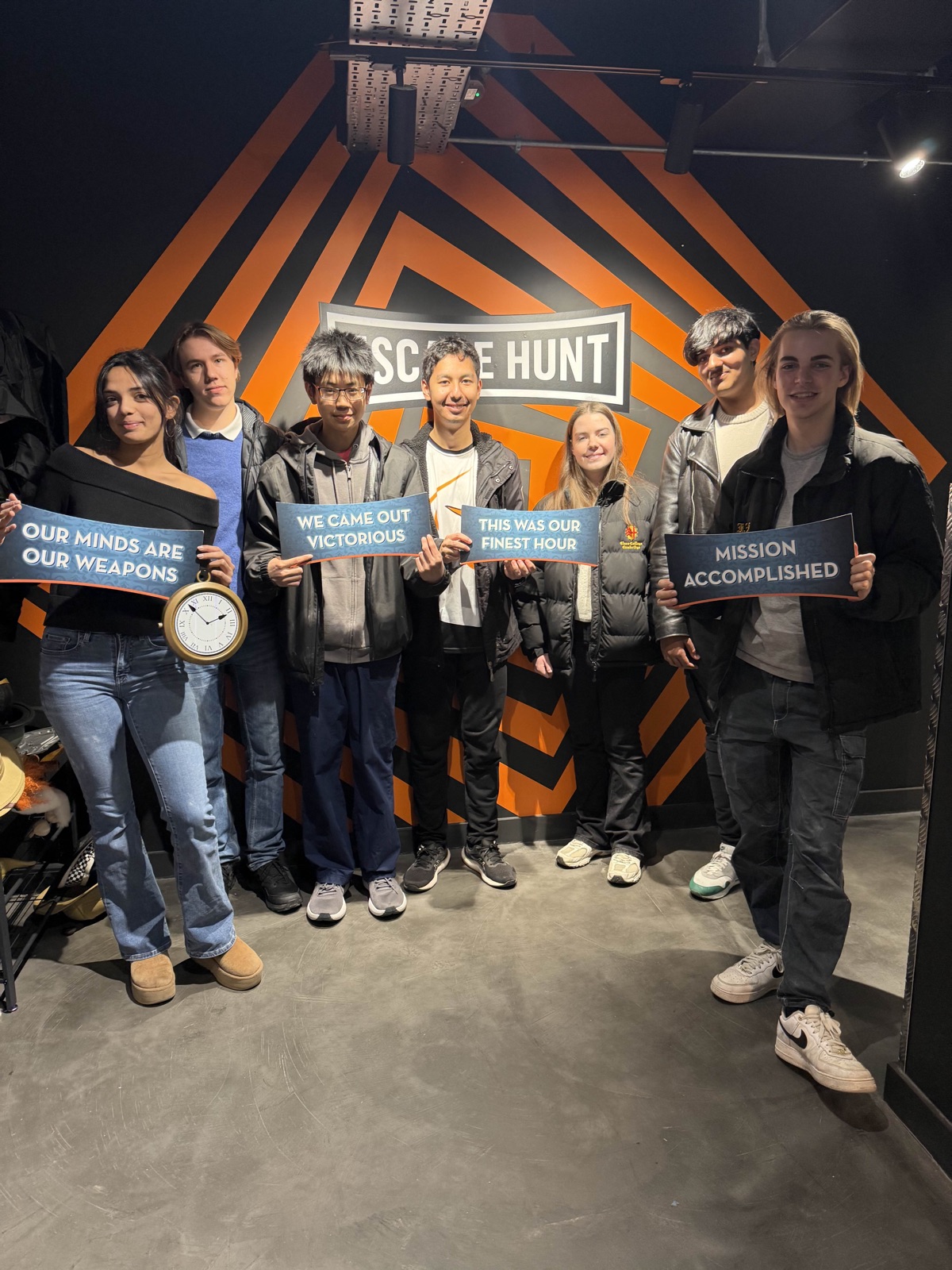 Society members holding celebratory signs after completing an escape room